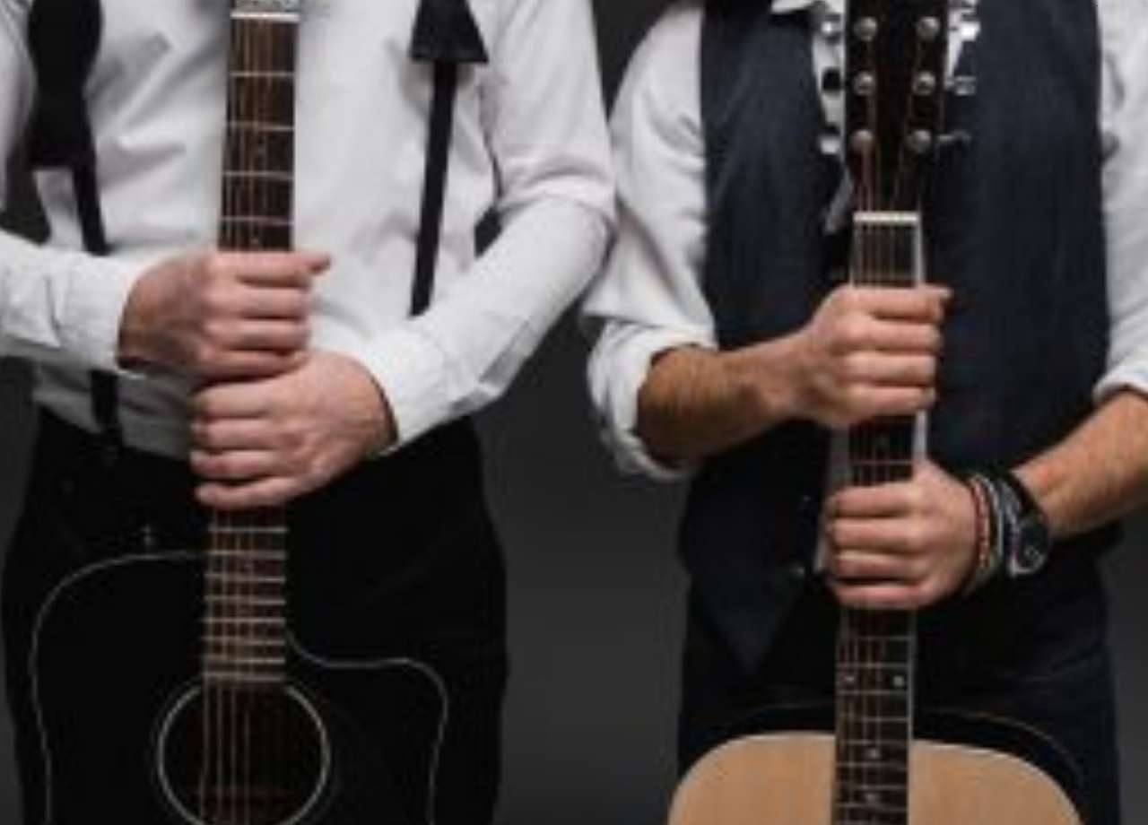 acoustic and electric guitar held by two men side by side