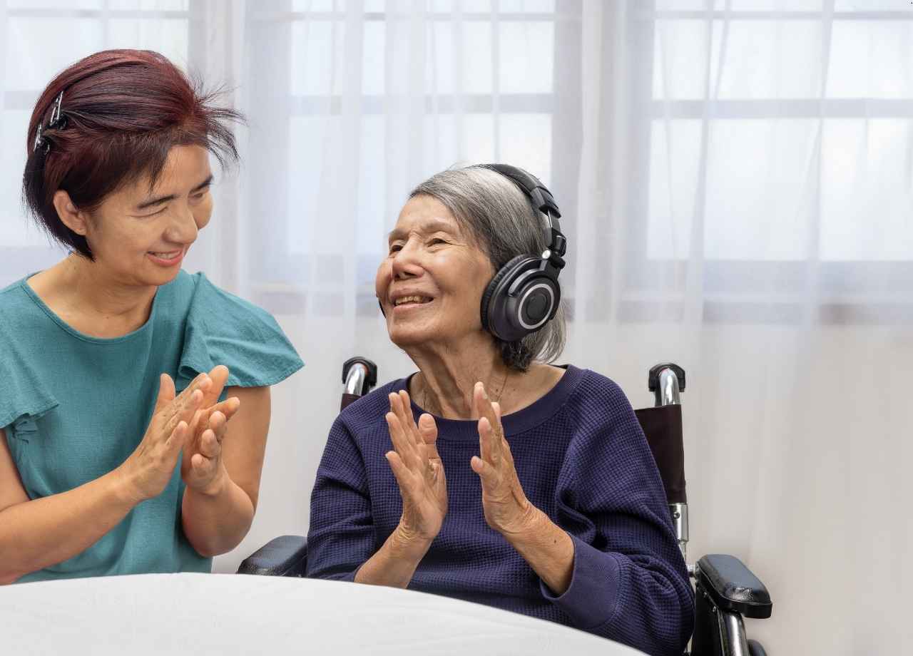 An old grandmother smiles as she's talking beside her grandmother