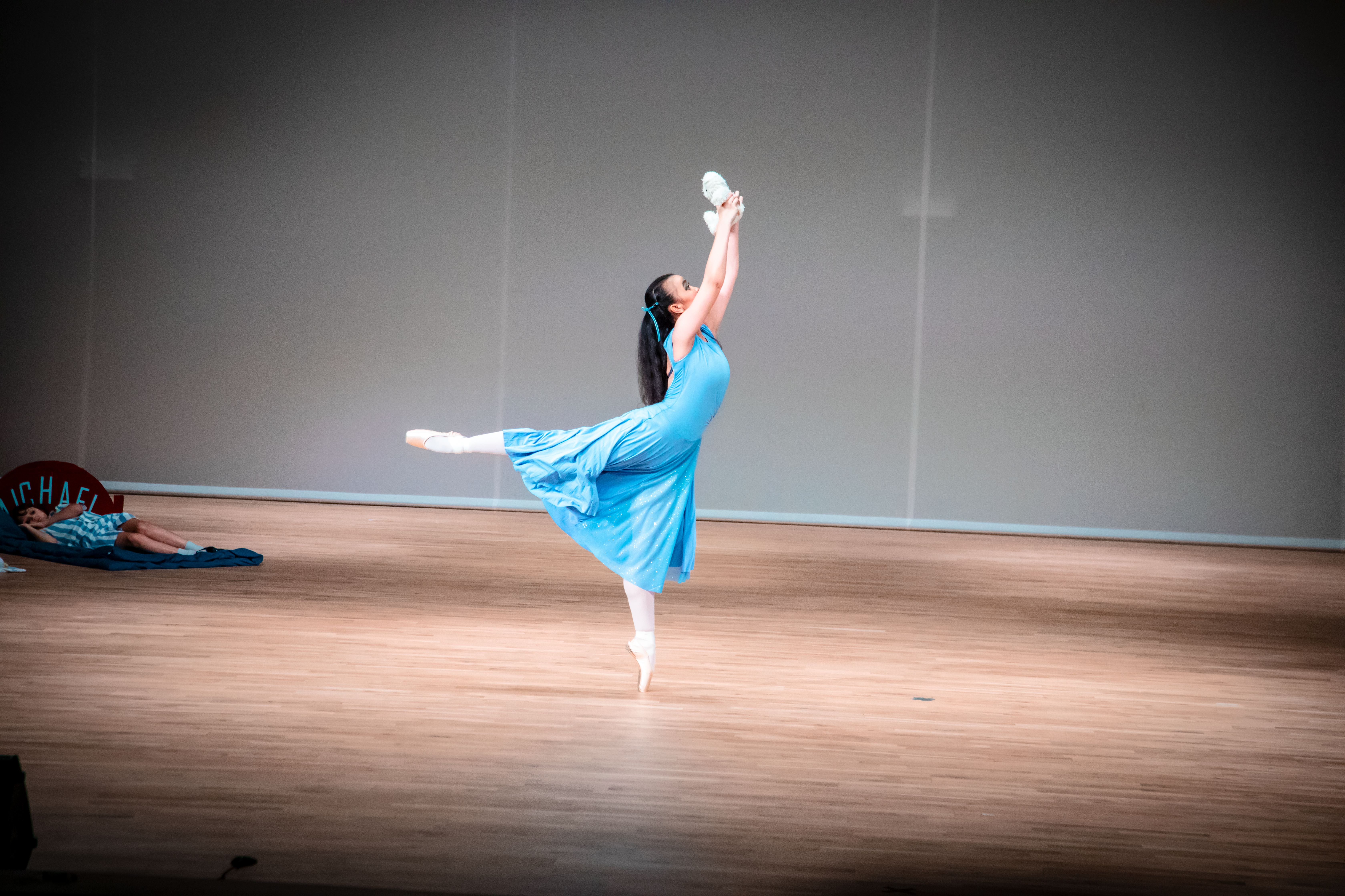 ballet dancer wearing blue attire and standing on one leg