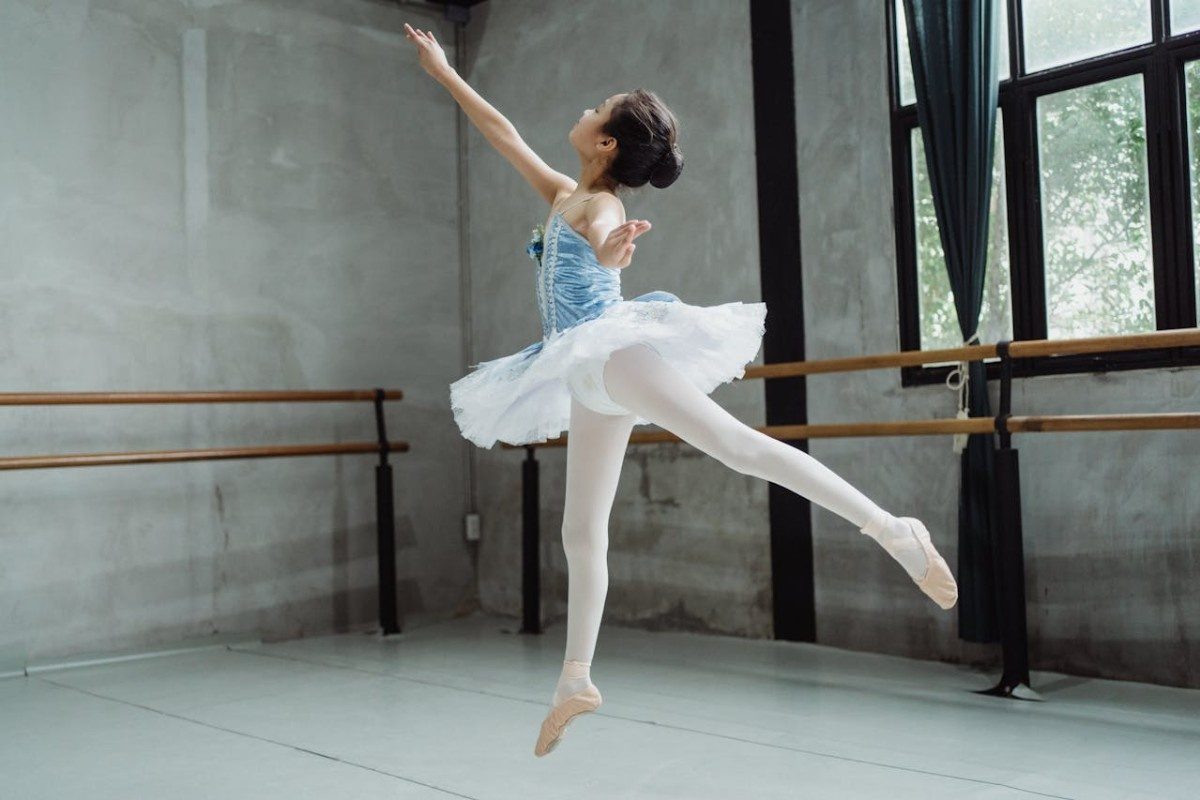 Ballerina girl performing ballet jump in studio