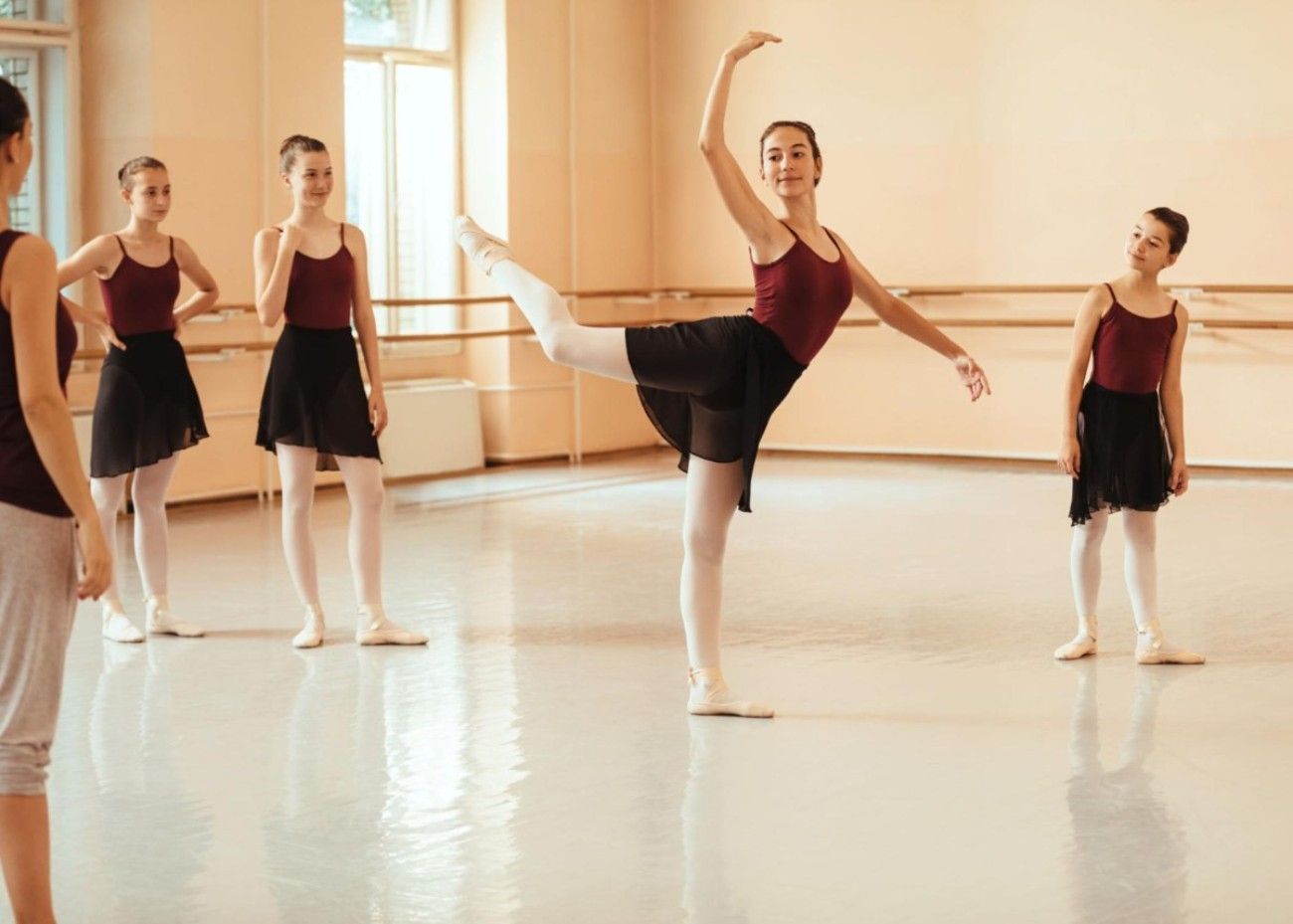 Ballerina posing in the middle of her class while her four colleagues look on