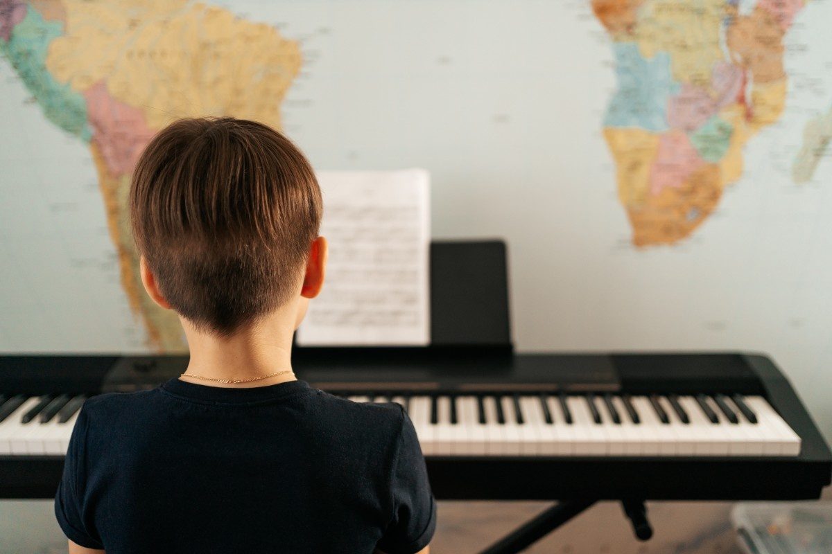 School boy playing piano at home