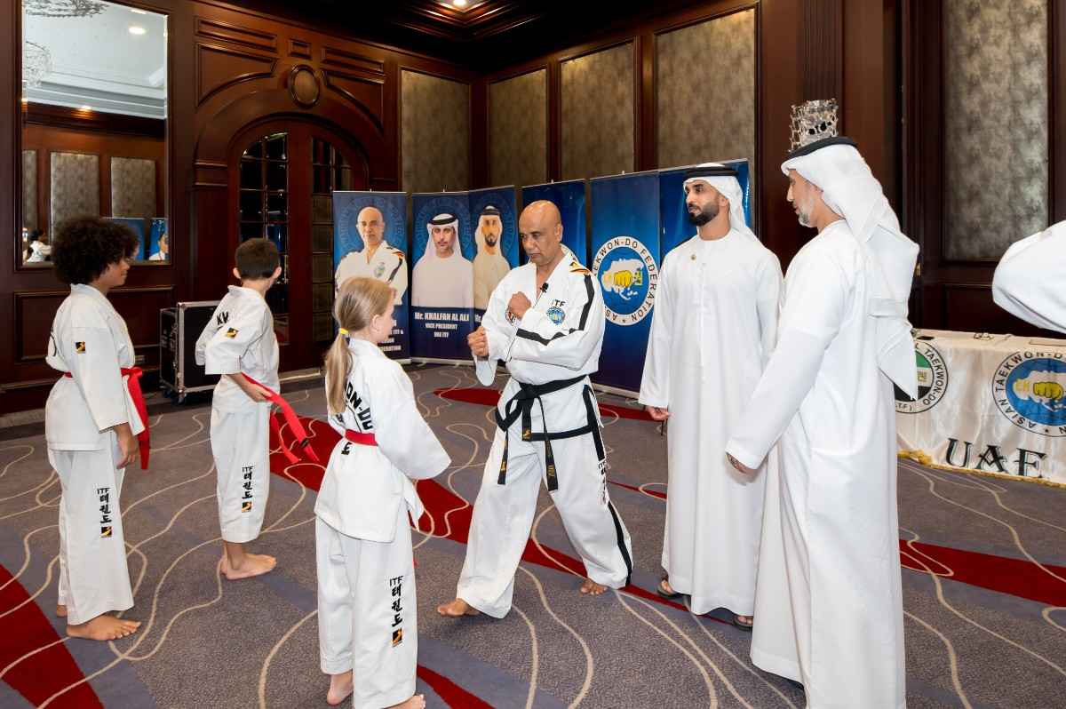 A man taching children taekwondo as children watch.
