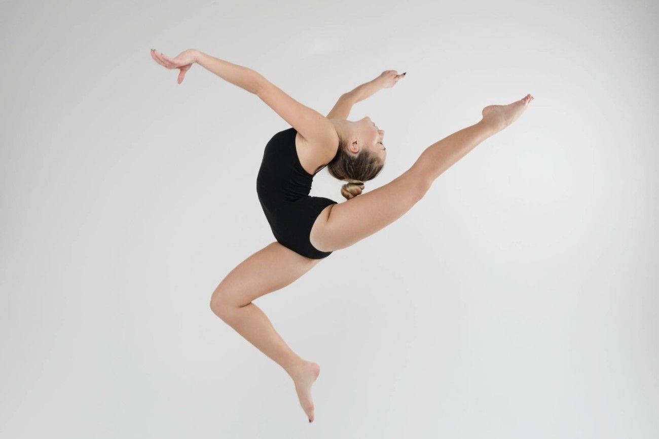 A young ballet dancer in mid air doing a ballet pose