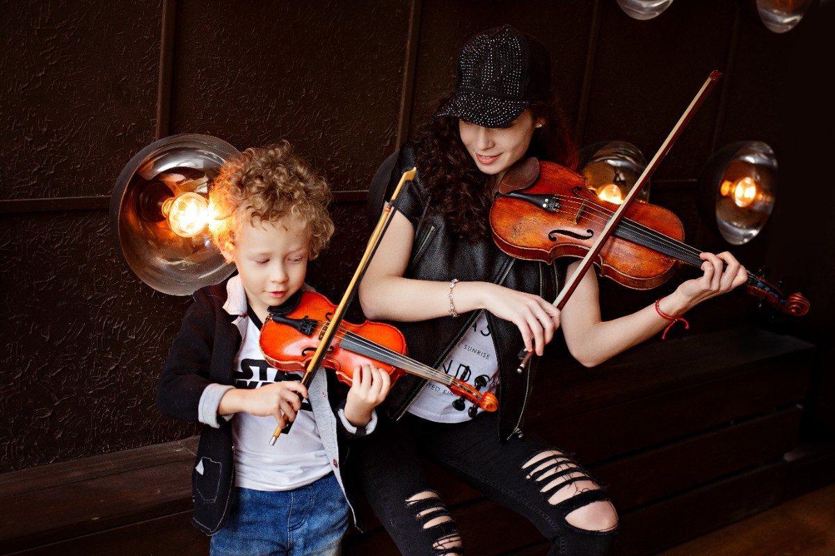 A young beautiful girl in black clothes sits next to her curly blonde with her son