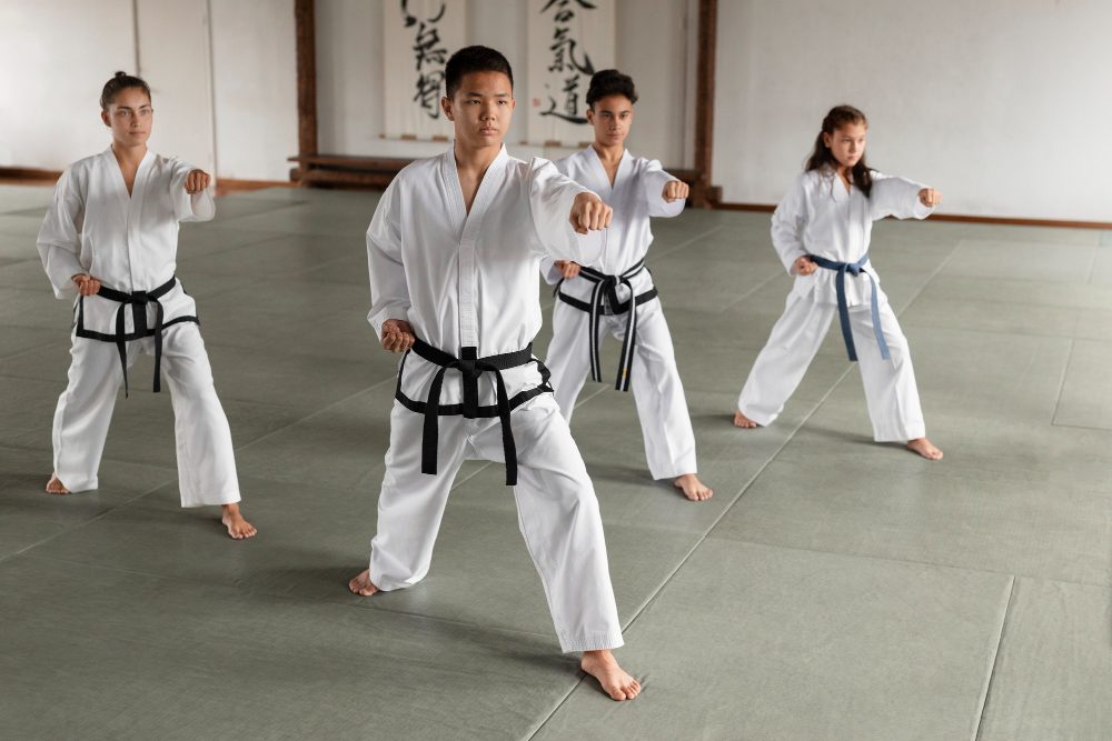 taekwondo class of four young students in white uniforms