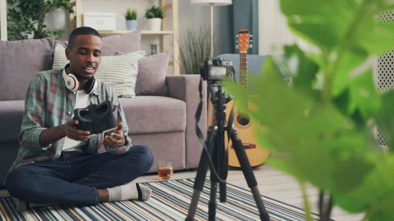 A man sitting down in his lounge with his guitar by his side.