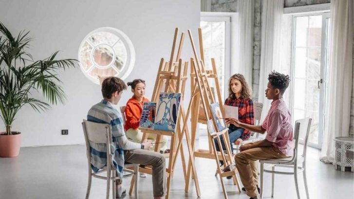 A group of children sitting in front of paintings and painting
