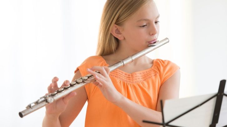 girl holding and playing a flute