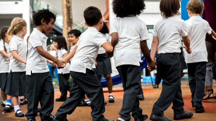 Group of diverse kindergarten students standing holding hands
