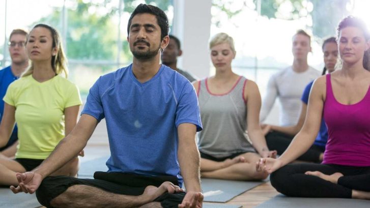 People sitting cross legged in yoga studio on yoga mats