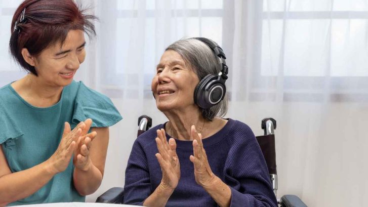 An old grandmother smiles as she's talking beside her grandmother