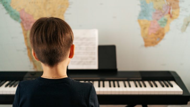 School boy playing piano at home
