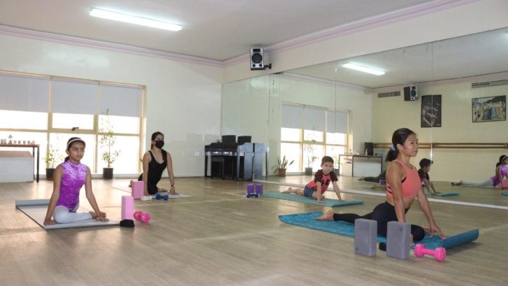 students in yoga class in a stretching pose