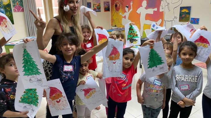 Children in art class holding up their paintings