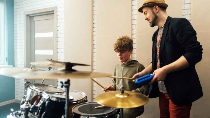 drum lessons being given to child by brother