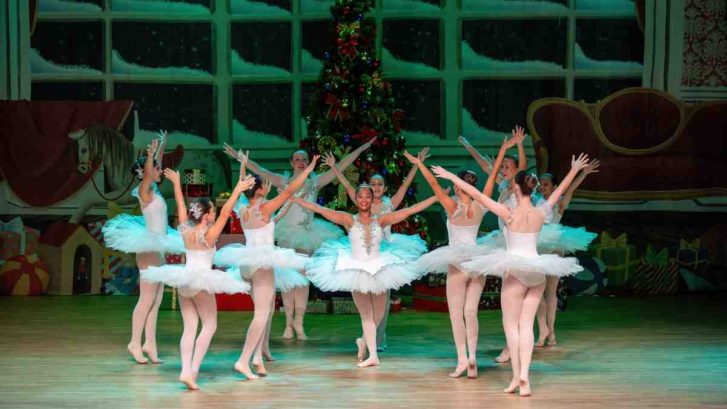 Female ballerinas surrounding one ballet dancer