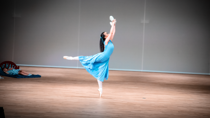ballet dancer wearing blue attire and standing on one leg