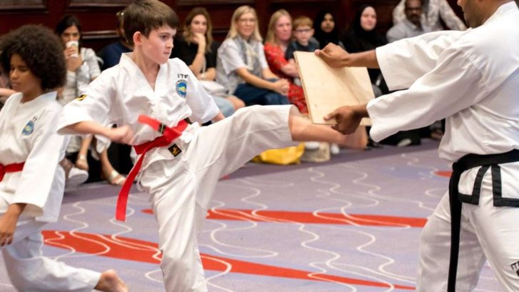taekwondo student breaking wooden board with a kick